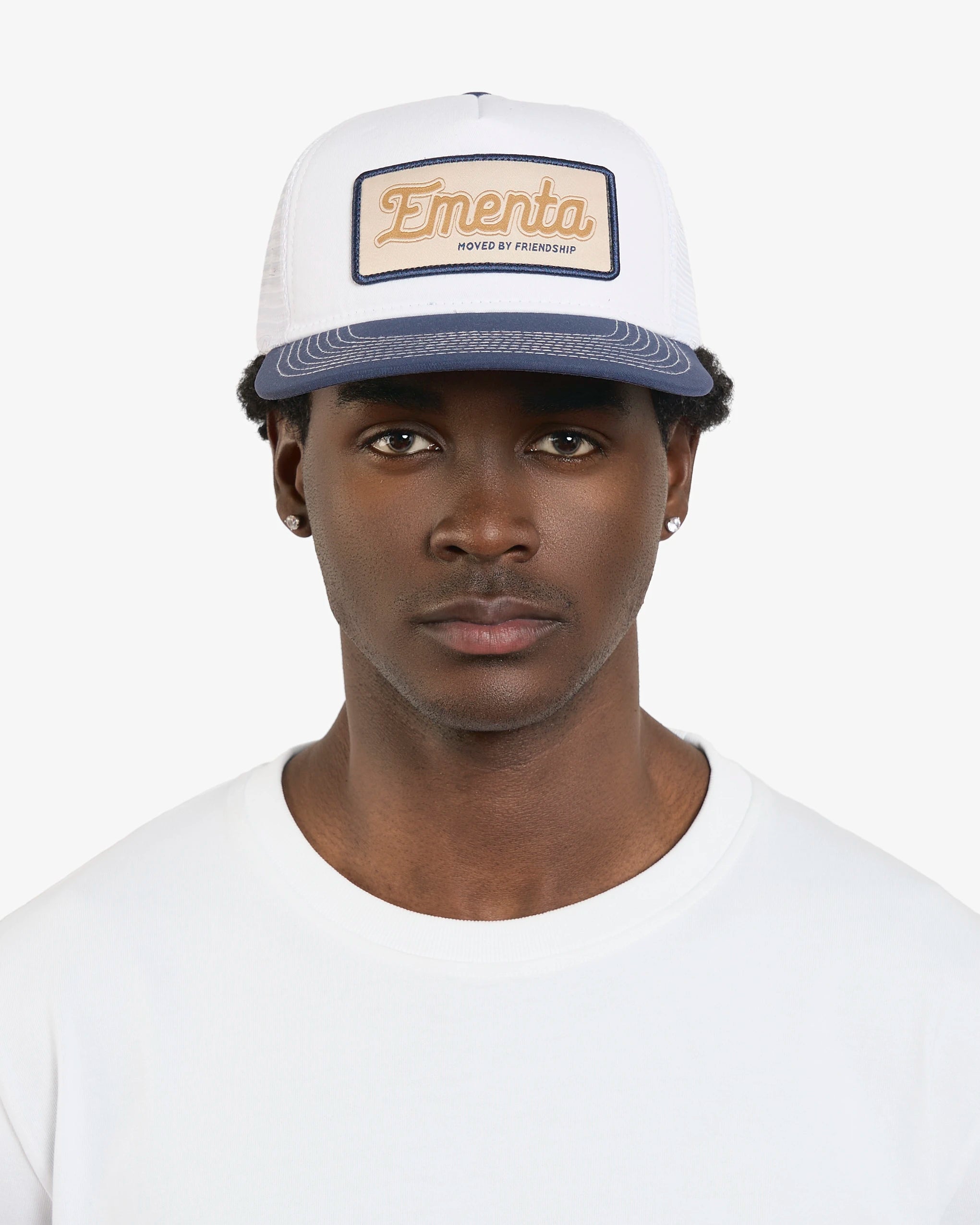 Classic breathable trucker cap design for comfort
Ementa patch with "Moved By Friendship" motto at the center
Visible white stitching for added detail
Adjustable strap with metal buckle for a customizable fit