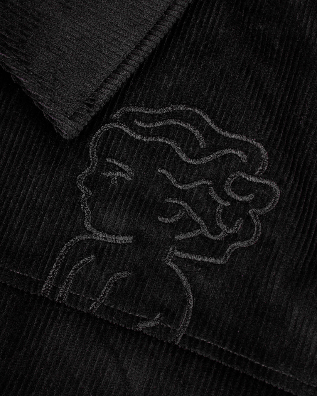 The Big Ikon Corduroy Jacket is made from durable black corduroy with a liquid-repellent coating, making it a reliable choice for various weather conditions. It features a puffed interior for warmth and comfort. On the chest, you'll find an embroidered Big Ikon logo, while the back showcases the motto "Moved by Friendship." The elasticated waist and cuffs provide an adjustable fit.