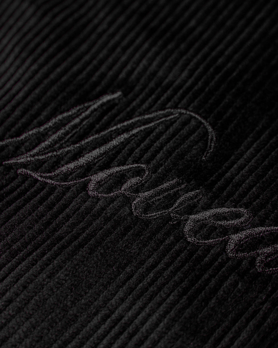 The Big Ikon Corduroy Jacket is made from durable black corduroy with a liquid-repellent coating, making it a reliable choice for various weather conditions. It features a puffed interior for warmth and comfort. On the chest, you'll find an embroidered Big Ikon logo, while the back showcases the motto "Moved by Friendship." The elasticated waist and cuffs provide an adjustable fit.