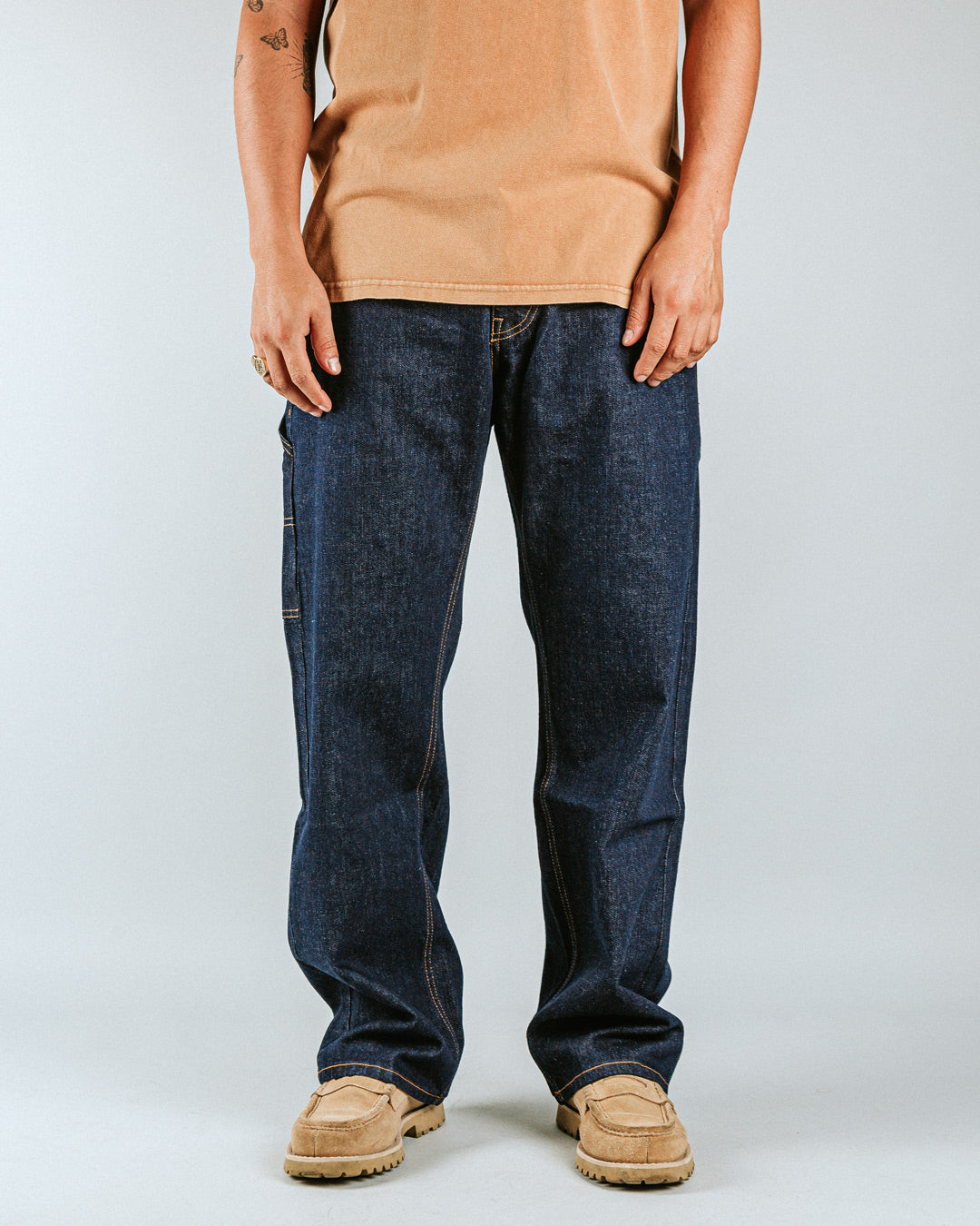 The Big Ikon Jeans Relaxed Fit Pants are designed with a baggy, relaxed straight fit and a mid-waist, offering comfort and ease of movement. The pants are crafted from blue raw denim, providing a timeless and durable look. They feature the Ikon logo embroidered in gold on the back pocket. The pants also include two front pockets, two back pockets, and one side pocket for practical storage.