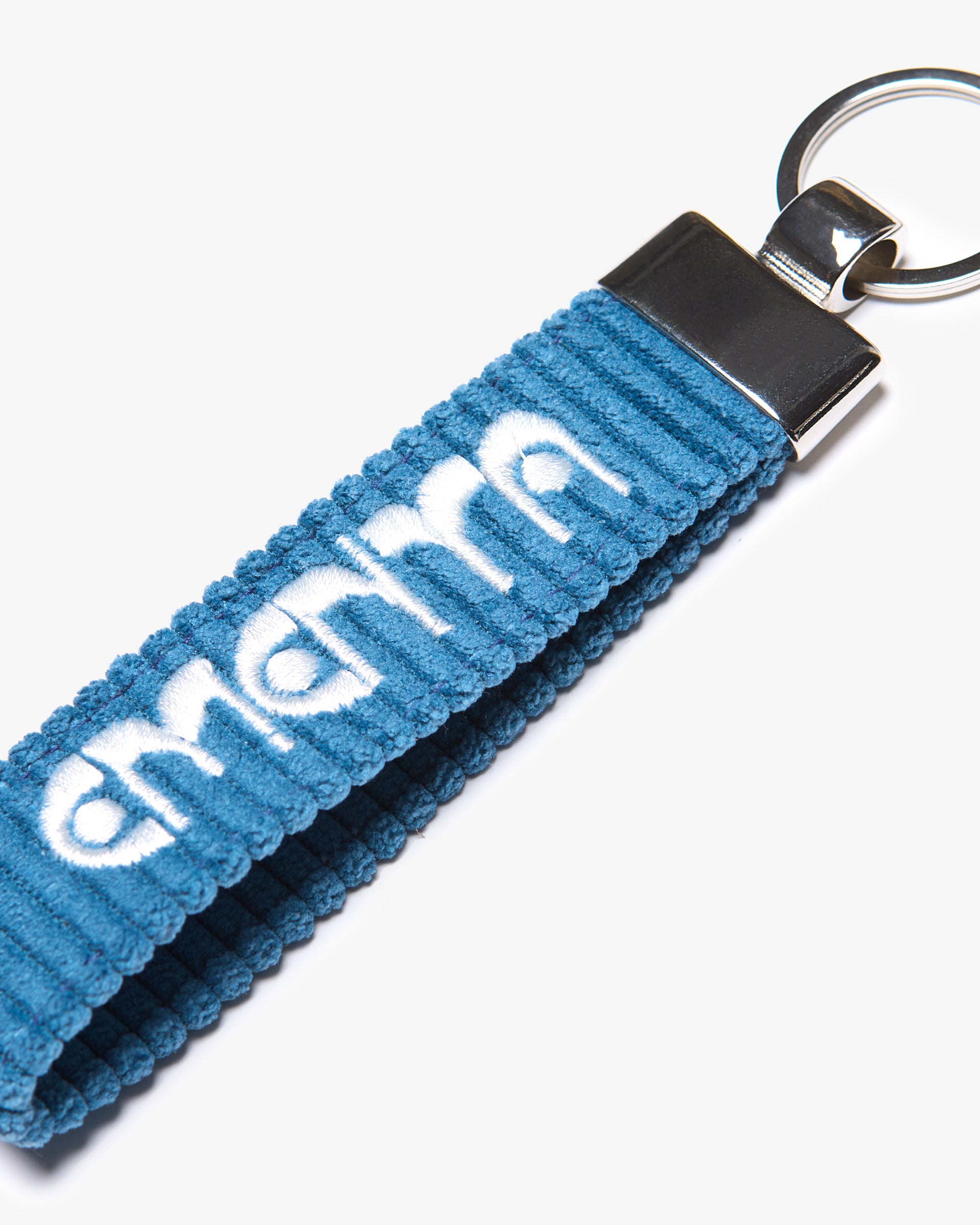 A corduroy keychain with the Ementa Dots logo in a metal finish.
Comes with a sturdy key ring. 
Simple, durable, and easy to carry.
The corduroy band measures 10,5cm in width and 2,5cm in length.