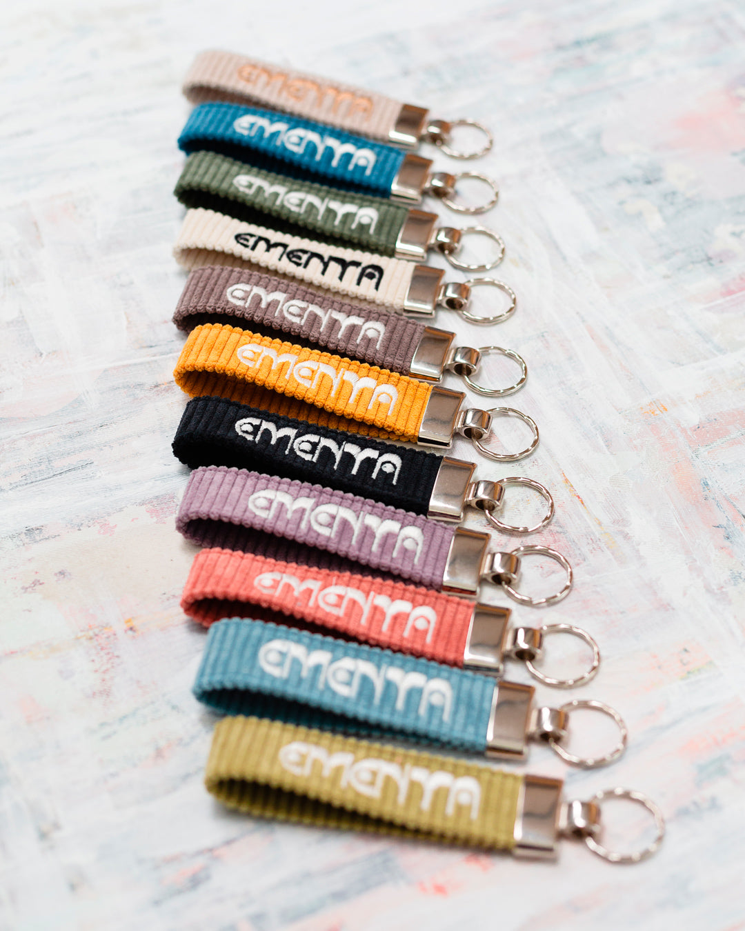 A corduroy keychain with the Ementa Dots logo in a metal finish.
Comes with a sturdy key ring.
Simple, durable, and easy to carry.
The corduroy band measures 10,5cm in width and 2,5cm in length.