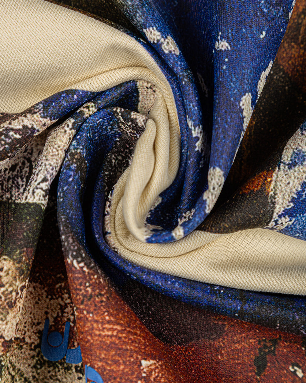 The Kápodi T-shirt in off-white features a striking front print, created through a hand-painted canvas made by an artist and later photographed and printed. Overlaid on this unique artwork is the Ementa dots logo in blue, adding a bold accent. Made from thick cotton for added comfort and a better fit, this unisex piece offers a regular fit, combining artistic craftsmanship with timeless style.