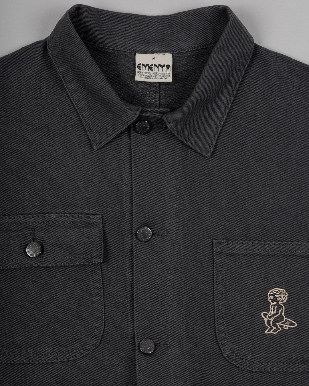 The Kit Ikon Twill Jacket in dark grey features a versatile and timeless design, made for durability and comfort.
Featuring a classic button-down front, a structured collar, wrist cuffs, chest pockets for functionality, and an embroidered design for added flair, this jacket is perfect for casual outings or workwear.