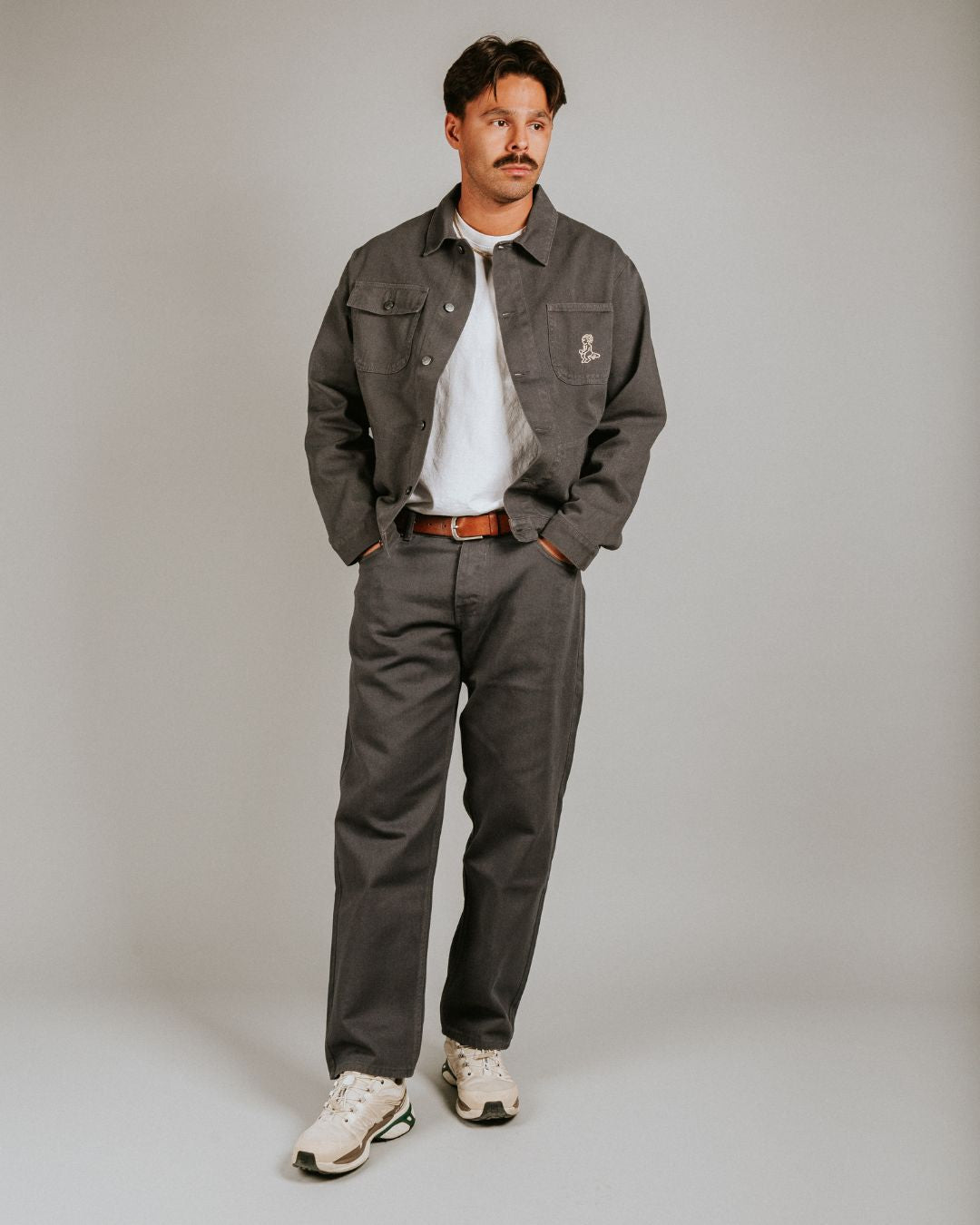 The Kit Ikon Twill Jacket in dark grey features a versatile and timeless design, made for durability and comfort.
Featuring a classic button-down front, a structured collar, wrist cuffs, chest pockets for functionality, and an embroidered design for added flair, this jacket is perfect for casual outings or workwear.