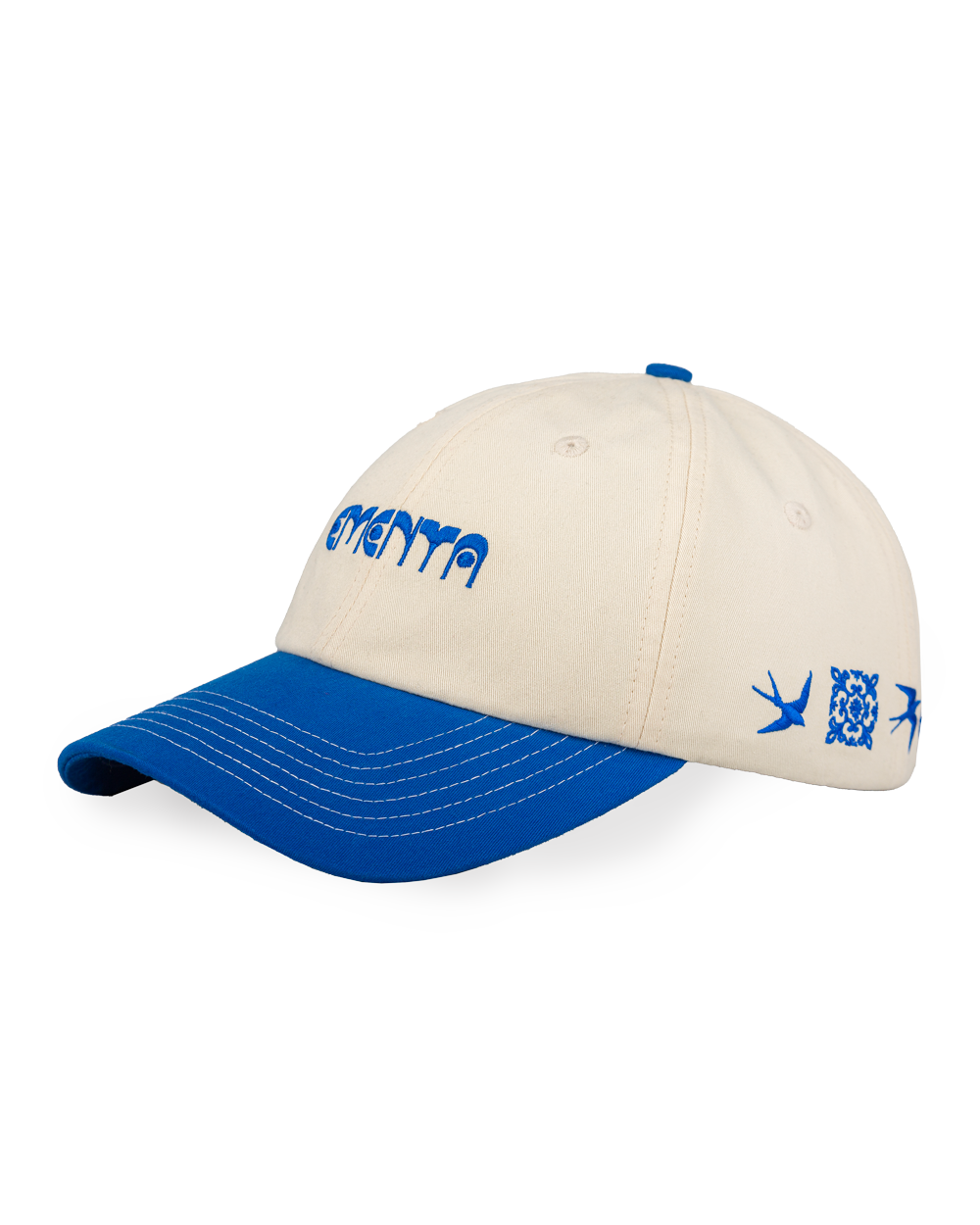 The Lisa Cap is a classic six-panel cap crafted from durable 100% cotton twill, inspired by Lisbon’s cultural heritage. It features an off-white crown and a royal blue curved brim, with visible white stitching. The front panel showcases the Ementa Dots logo embroidered in royal blue, while the side is adorned with the Lisa design, a tribute to Lisbon’s iconic tiles and swallows. An adjustable back strap ensures a comfortable and customizable fit, making this cap a timeless and versatile addition to any ward