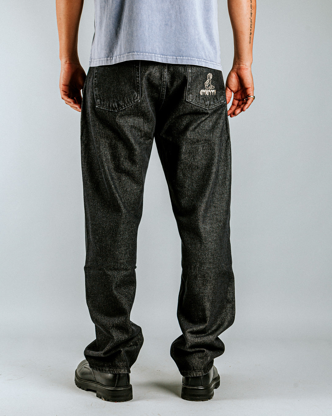 Relaxed-fit jeans made from black rinsed denim, designed for comfort and durability with a focus on providing the perfect fit. The jeans feature embroidered logos on the front and back for added detail.