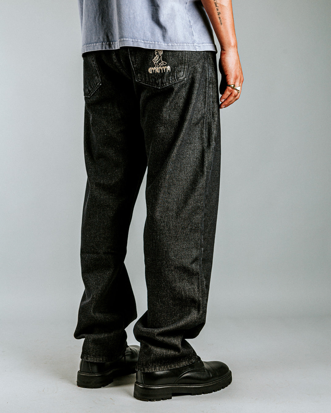 Relaxed-fit jeans made from black rinsed denim, designed for comfort and durability with a focus on providing the perfect fit. The jeans feature embroidered logos on the front and back for added detail.
