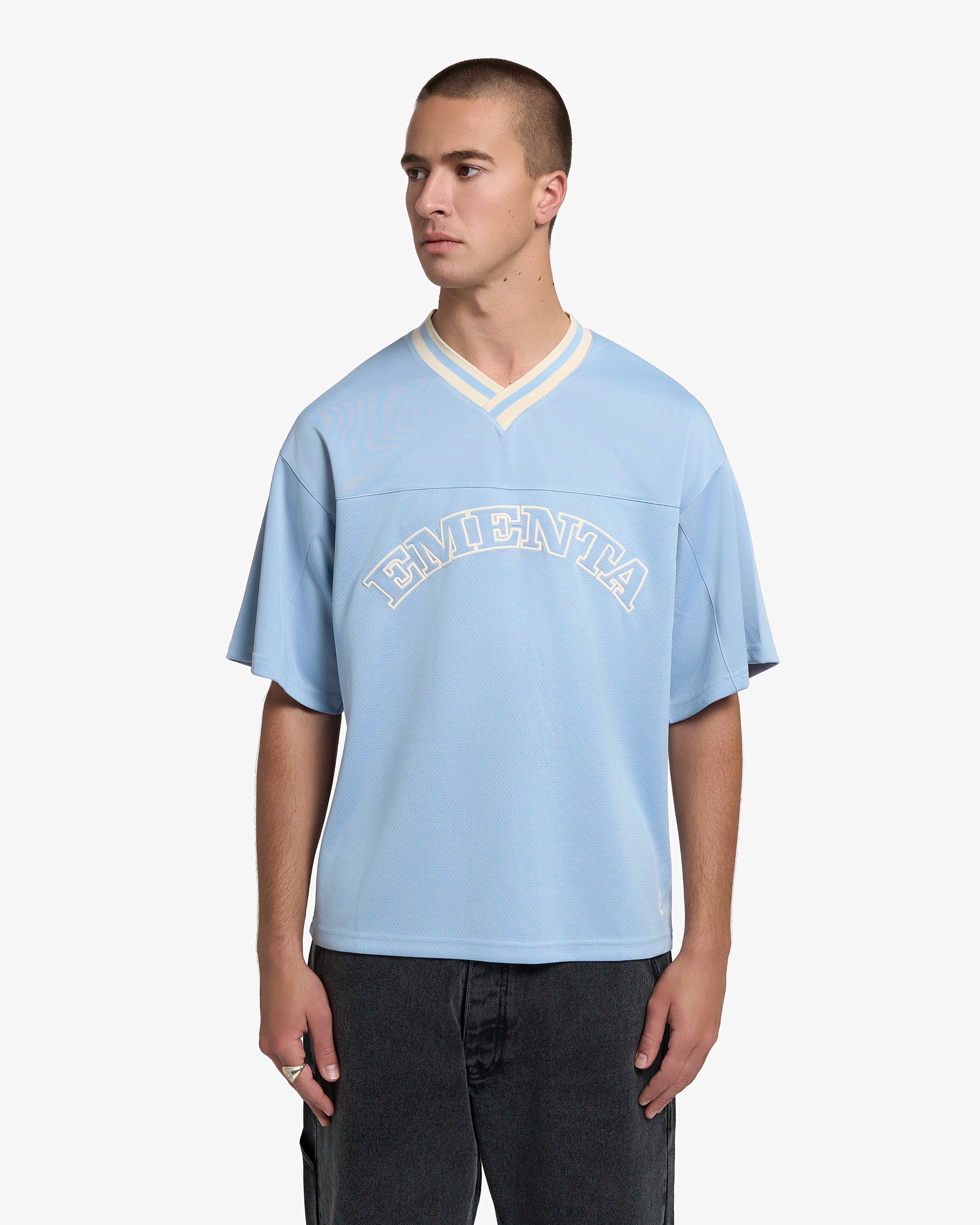 Breathable mesh fabric on the lower half, cotton-poly blend on the upper half
Oversized fit
Sky blue color with off-white accents
Large 'EMENTA' embroidery on the chest, small branded detail embroidered on the bottom right
V-neck collar with double green stripes
Oversized sleeves for a relaxed silhouette
Part of a kit – matching shorts available online
Machine washable