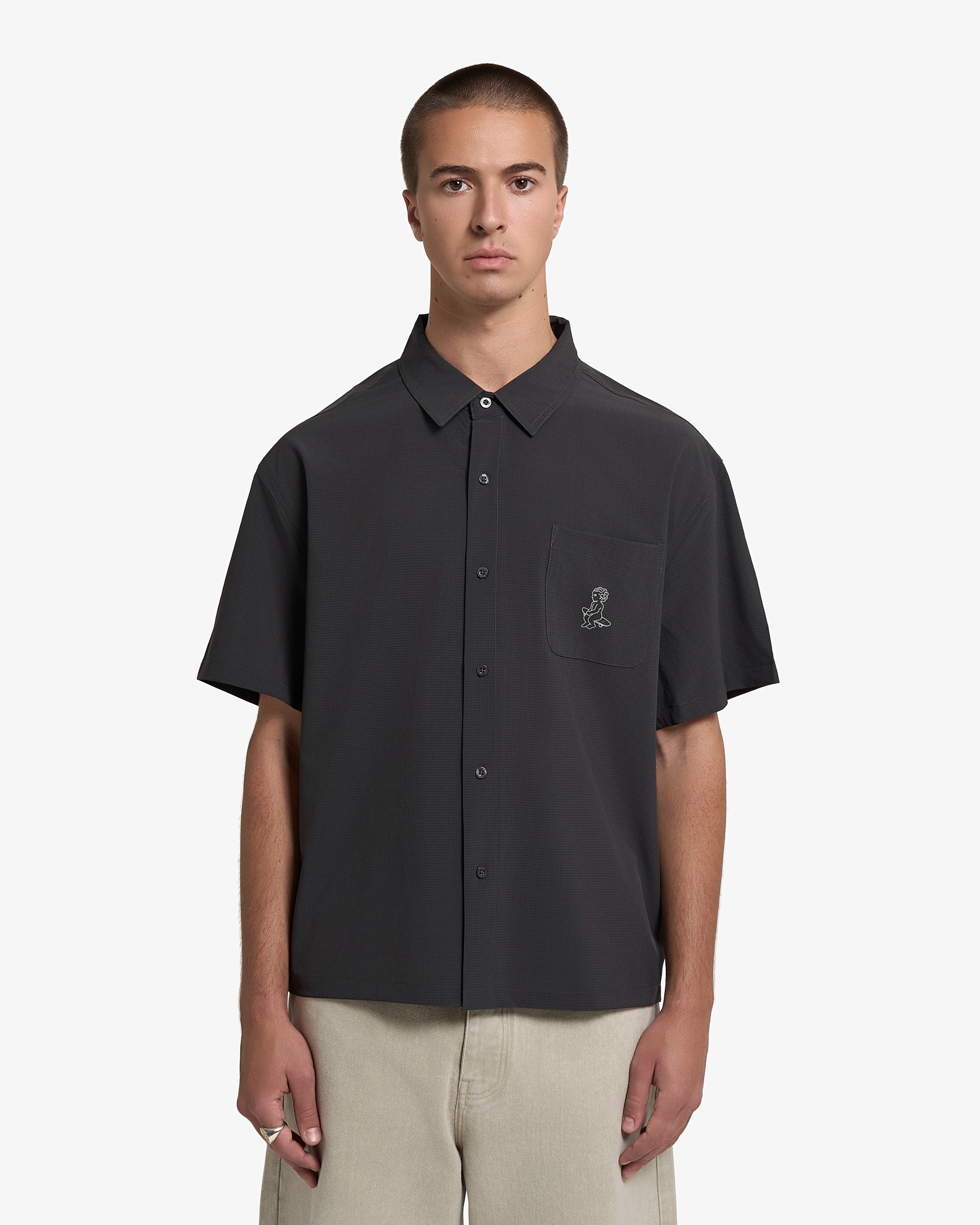 Short sleeve button-up shirt designed for everyday wear
Lightweight textured fabric with a subtle grid structure and dry hand feel
Boxy fit with a straight, slightly cropped silhouette
Front button closure with a chest pocket
Ikon logo printed on the front pocket
Black color with a tonal finish