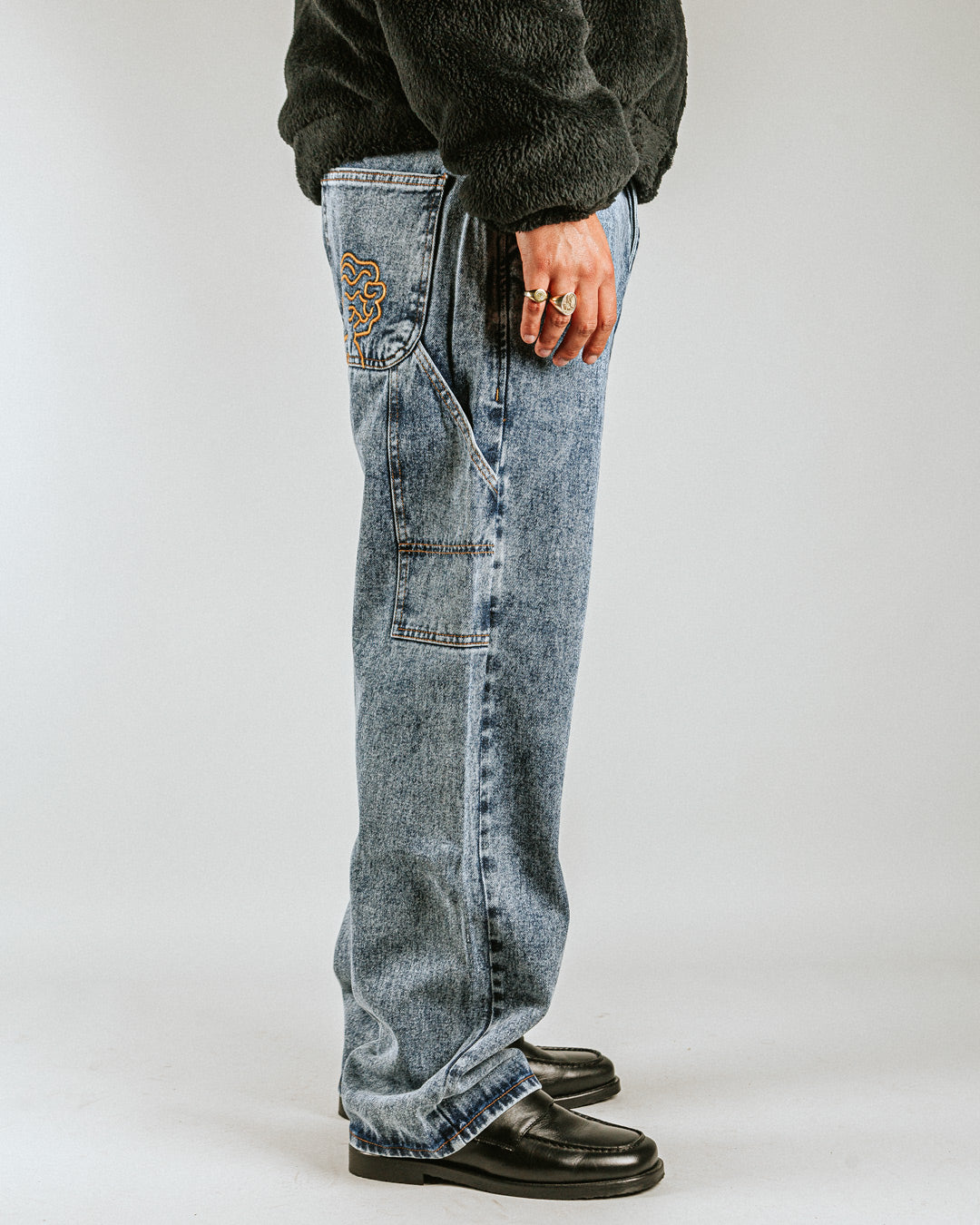 The Big Ikon Jeans Relaxed Fit Pants are designed with a baggy, relaxed straight fit and a mid-waist, offering comfort and ease of movement. The pants are crafted from blue fade-out denim, providing a timeless and durable look. They feature the Ikon logo embroidered in gold on the back pocket. The pants also include two front pockets, two back pockets, and one side pocket for practical storage.