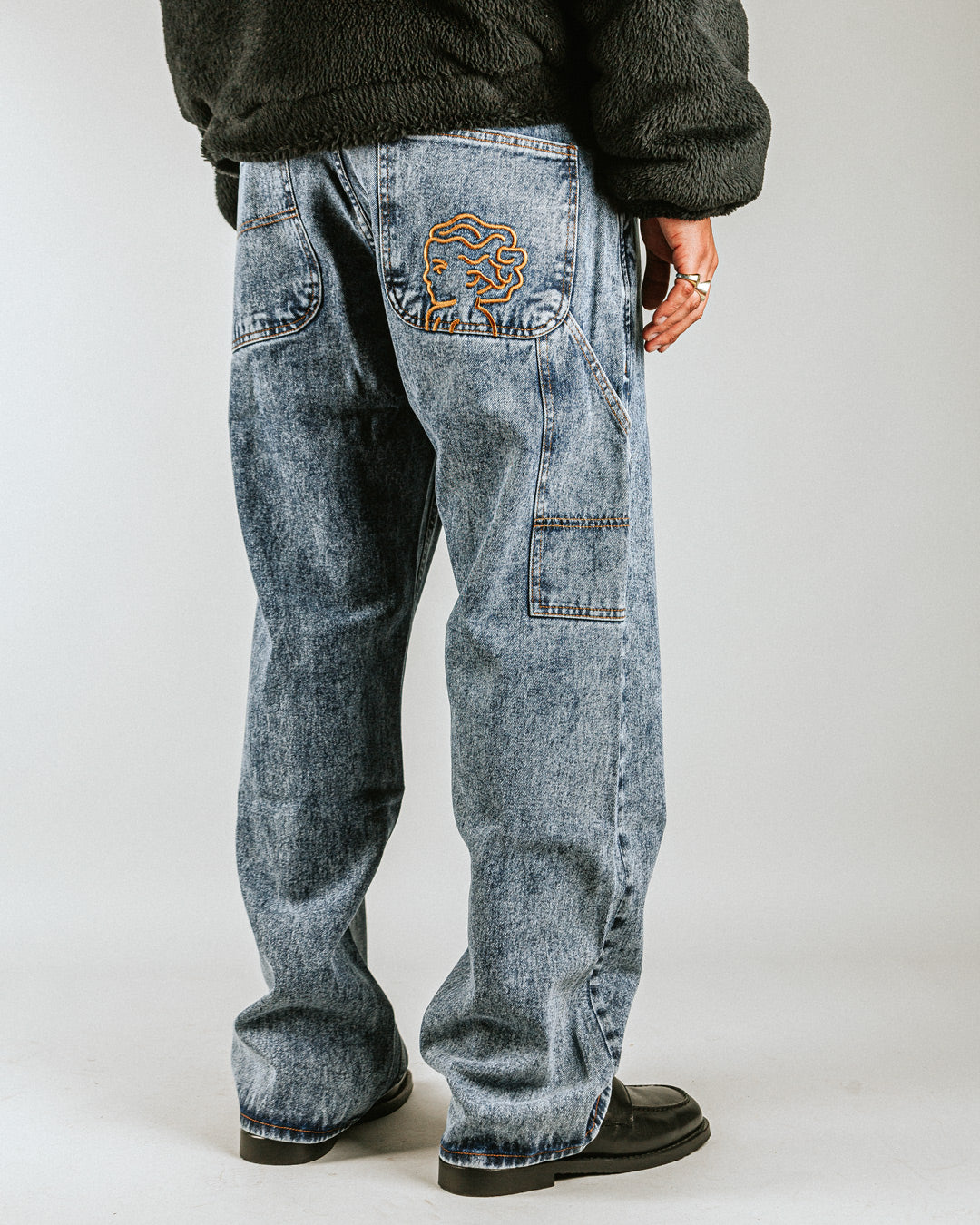 The Big Ikon Jeans Relaxed Fit Pants are designed with a baggy, relaxed straight fit and a mid-waist, offering comfort and ease of movement. The pants are crafted from blue fade-out denim, providing a timeless and durable look. They feature the Ikon logo embroidered in gold on the back pocket. The pants also include two front pockets, two back pockets, and one side pocket for practical storage.