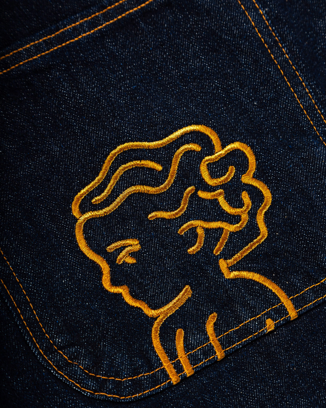The Big Ikon Jeans Relaxed Fit Pants are designed with a baggy, relaxed straight fit and a mid-waist, offering comfort and ease of movement. The pants are crafted from blue raw denim, providing a timeless and durable look. They feature the Ikon logo embroidered in gold on the back pocket. The pants also include two front pockets, two back pockets, and one side pocket for practical storage.