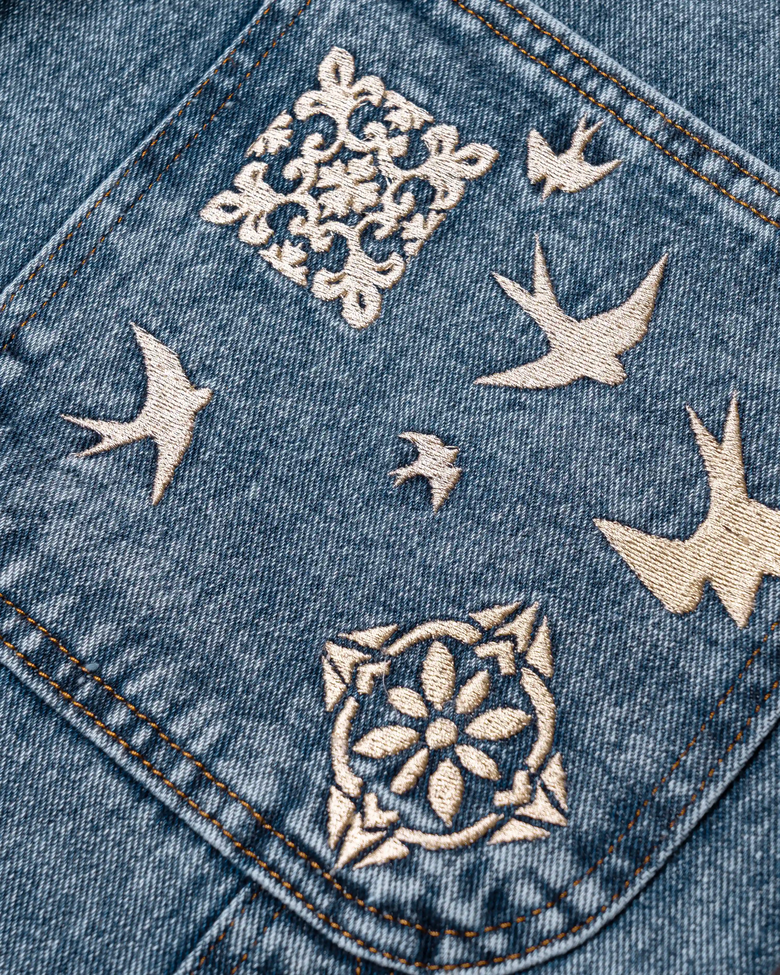 100% Cotton denim
Blue fade out wash
Embroidered Lisbon's tiles and swallows on back pocket and front leg
2 angled front pockets with classic coin pocket
2 back patch pockets featuring decorative embroidery
2 side utility pockets with reinforced panel construction
Relaxed, knee-length fit with wide leg opening
Branded EMENTA patch on rear waistband
Made in Portugal