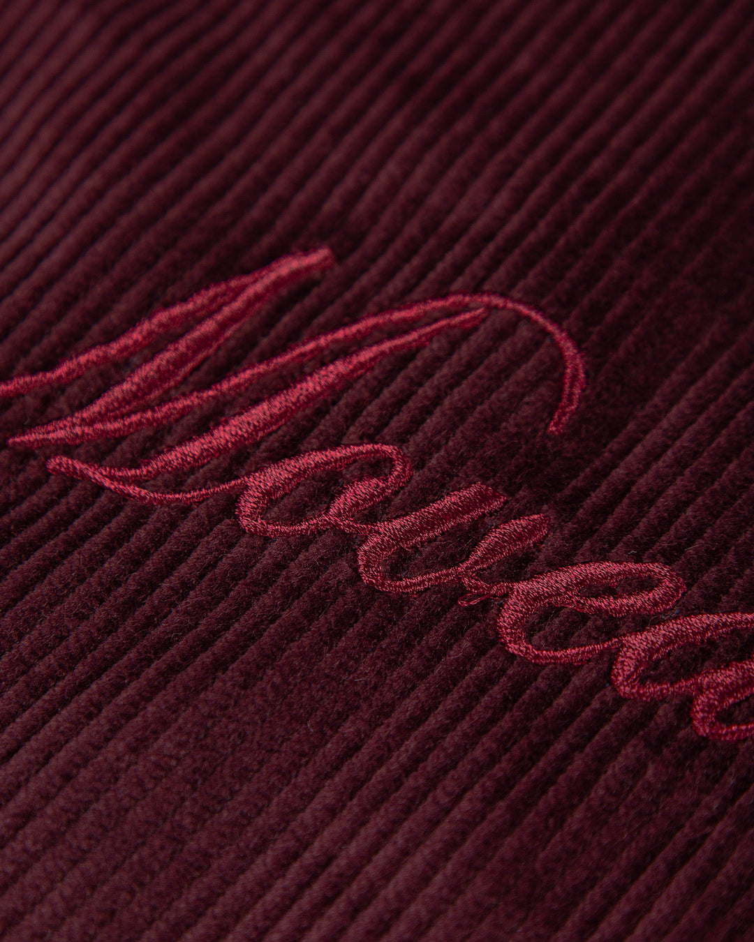 The Big Ikon Corduroy Jacket is made from durable burgundy corduroy with a liquid-repellent coating, making it a reliable choice for various weather conditions. It features a puffed interior for warmth and comfort. On the chest, you'll find an embroidered Big Ikon logo, while the back showcases the motto "Moved by Friendship." The elasticated waist and cuffs provide an adjustable fit.