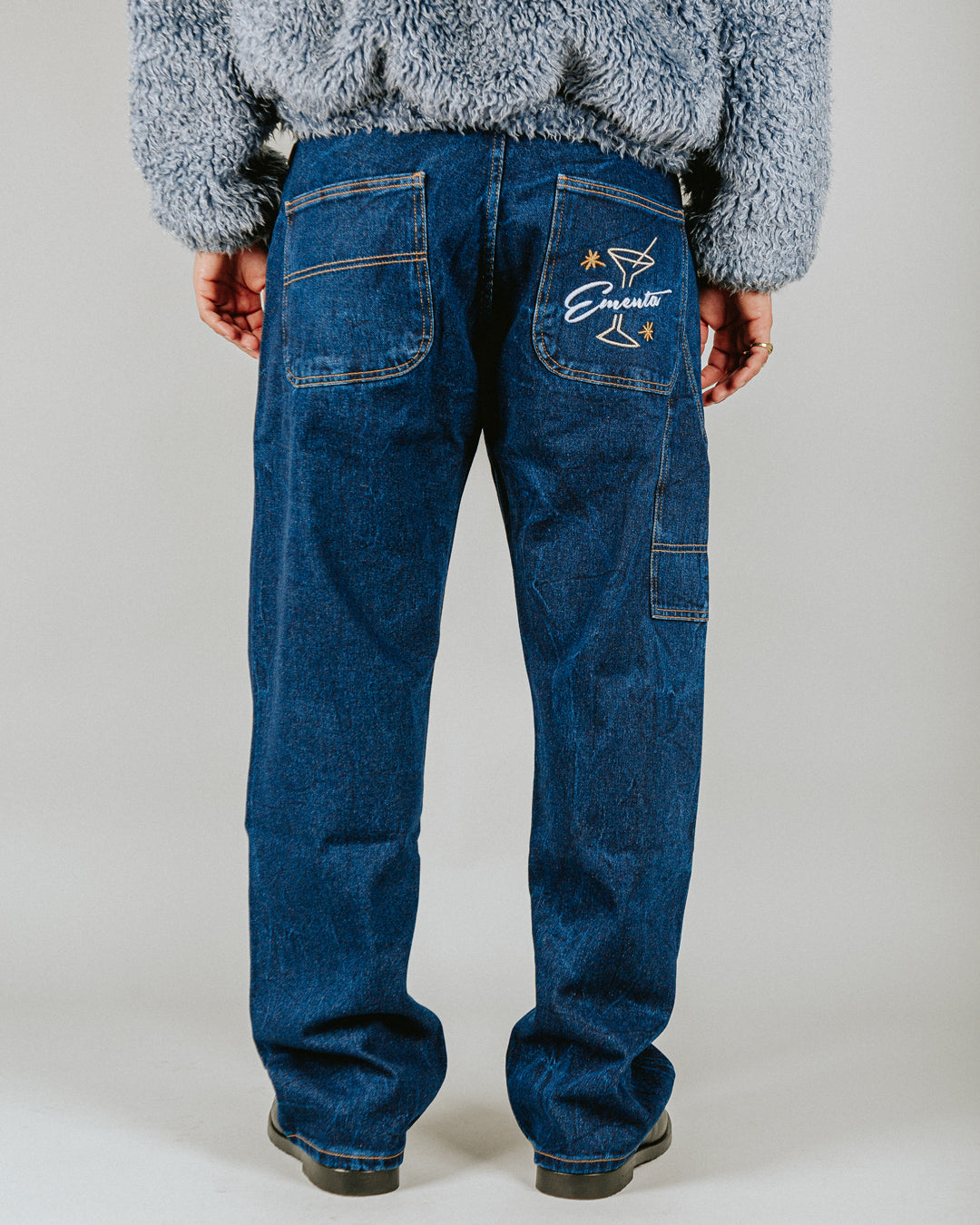 Relaxed-fit jeans made from blue marble stone-washed denim, designed for comfort and durability with a focus on providing the perfect fit. The jeans feature the cocktail design embroidered on the back pocket for added detail. Equipped with two back pockets, two front pockets, and one side pocket for practical storage.