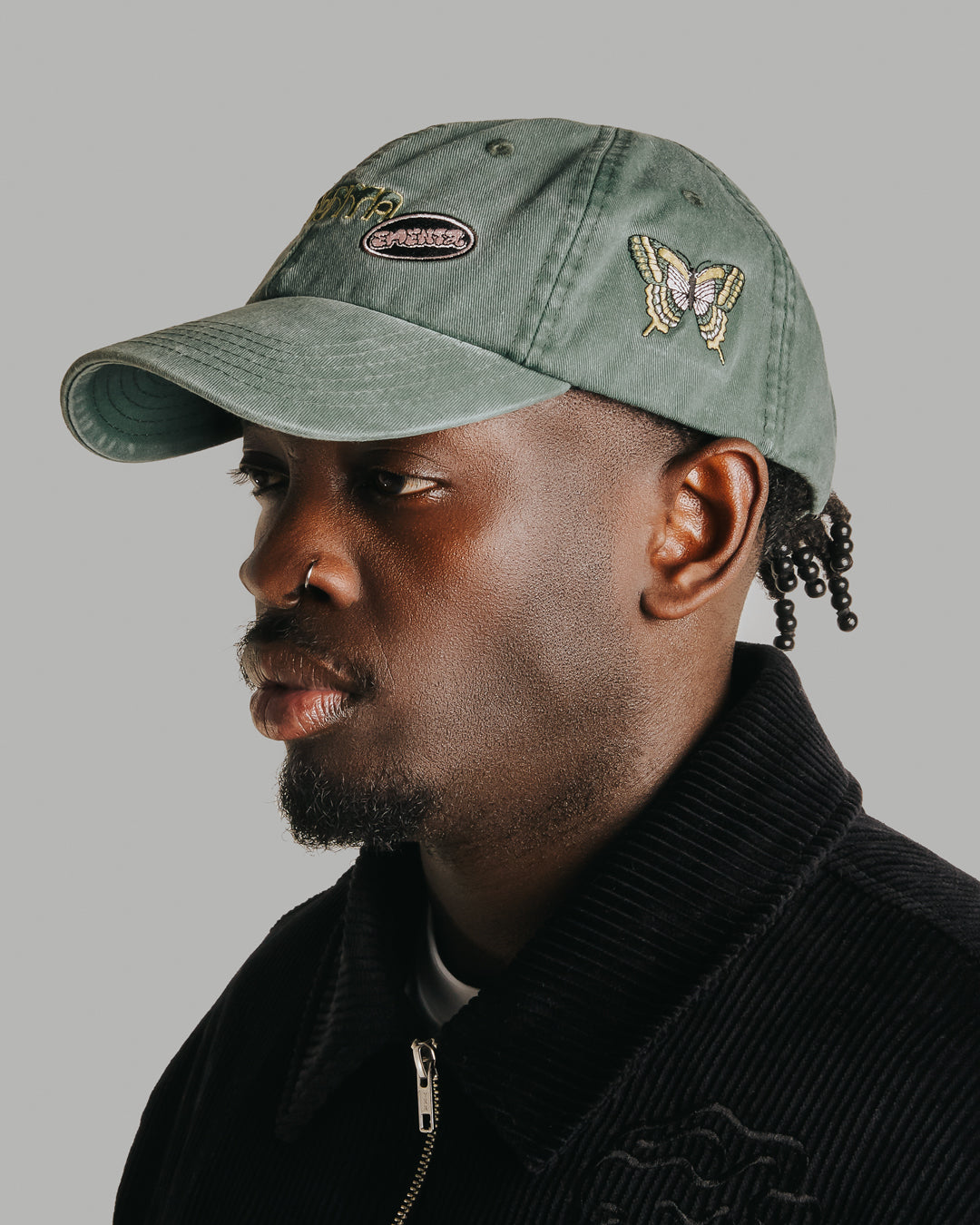 The Dots Patch Cap is a classic six-panel cap crafted from 100% cotton, ensuring a comfortable fit and durable wear. It comes in a green washed color, enhanced by a curved brim. The cap is decorated with multiple embroidered patches, adding character to the design.