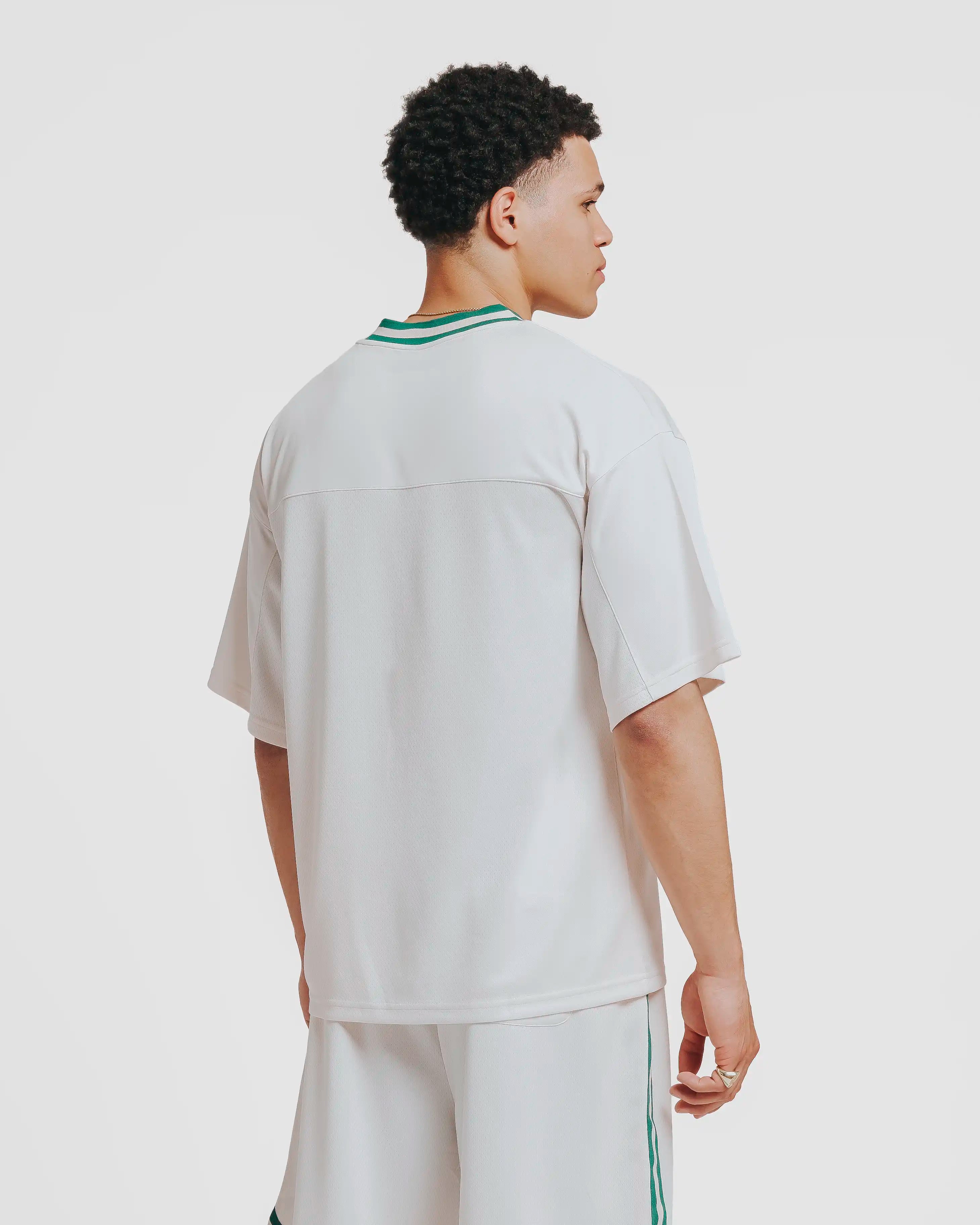 Breathable mesh fabric on the lower half, cotton-poly blend on the upper half
Oversized fit
White color with green accents
Large 'EMENTA' embroidery on the chest, small branded detail embroidered on bottom right
V-neck collar with double green stripes
Oversized sleeves for a relaxed silhouette
Part of a kit – matching shorts available online
Machine washable