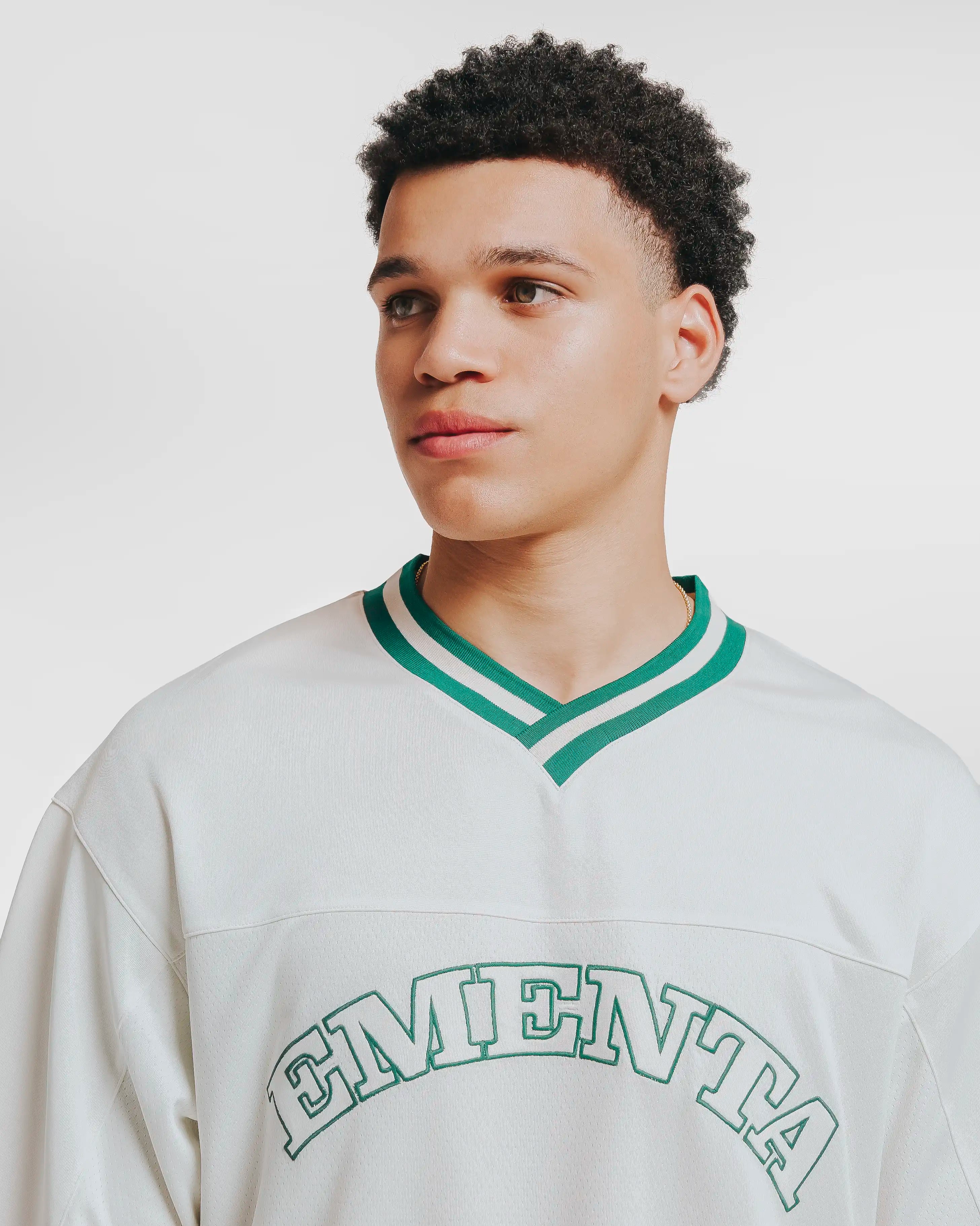 Breathable mesh fabric on the lower half, cotton-poly blend on the upper half
Oversized fit
White color with green accents
Large 'EMENTA' embroidery on the chest, small branded detail embroidered on bottom right
V-neck collar with double green stripes
Oversized sleeves for a relaxed silhouette
Part of a kit – matching shorts available online
Machine washable