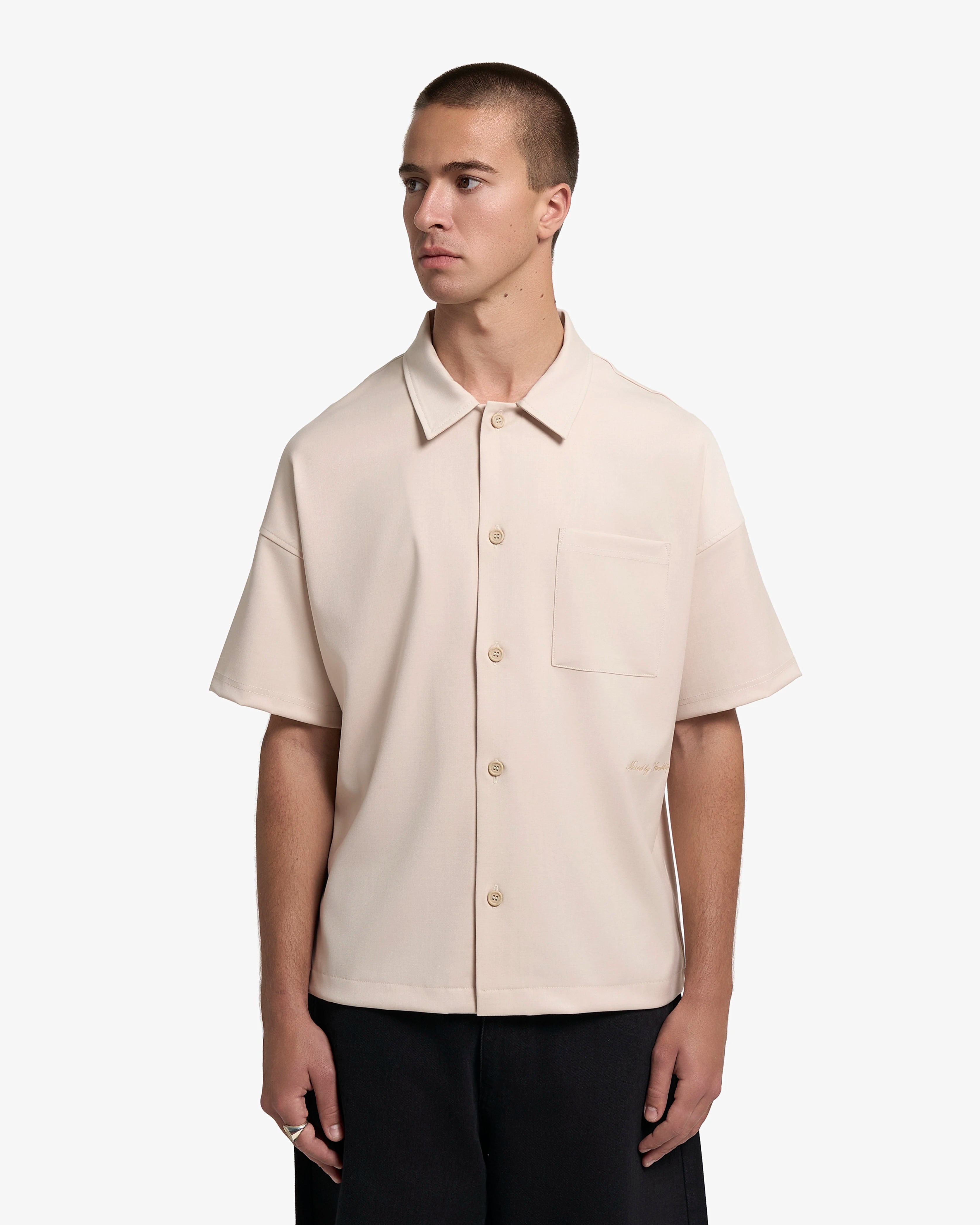 Short sleeve shirt developed with a tailored-inspired construction
Smooth midweight fabric with a soft drape and structured surface
Relaxed straight fit designed for everyday wear
Button closure with chest pocket and tonal “Moved by Friendship” embroidery
Off white tone with matching buttons and stitching
Made in Portugal